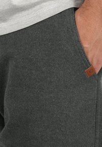 Pantalon de jogging gris en tissu doux avec une finition texturée. Doté de poches latérales et d'une petite étiquette en cuir marron.