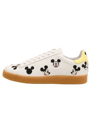 Biały sneaker z brązową podeszwą, ozdobiony wieloma czarno-białymi kreskówkowymi twarzami myszy i żółtą pętelką na pięcie.