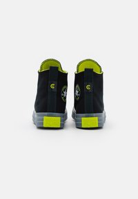 Czarne botki za kostkę z jasnooliwkowymi akcentami i szarymi gumowymi podeszwami. Posiadają charakterystyczne logo w kształcie gwiazdy oraz teksturowane przeszycia wokół góry.