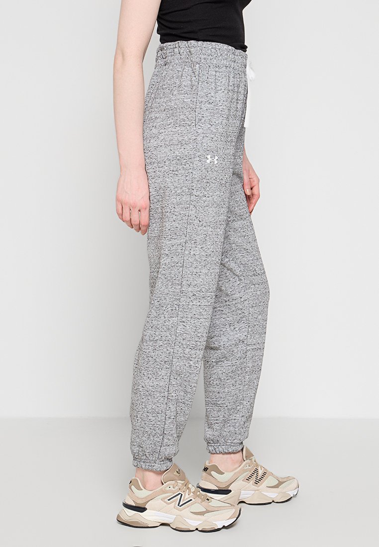 Joggers gris texturés avec une taille élastique et un cordon blanc, ornés d'un petit logo sur le côté. Associés à des baskets claires.
