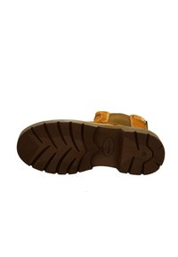 Brown rubber outsole with a textured pattern and logo; side detailing features tan leather accents and a stitched canvas upper.