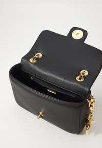 Black leather handbag with a textured finish, gold hardware, and a chain accent. Open top reveals a spacious interior with a zippered pocket.