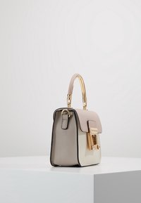 Piccola borsa a mano con una forma strutturata, realizzata in materiali beige e crema, con una chiusura dorata e un manico corto ed elegante.