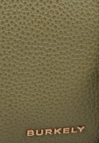 Materiale in pelle verde oliva con una texture a ciottoli; presenta il logo impresso "BURKELY" in oro metallico nella parte inferiore.