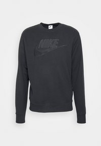 Mustapaita Nike, jossa on pyöreä kaula-aukko, pitkät hihat ja teksturoitu logo etupuolella. Valmistettu pehmeästä puuvillasekoitemateriaalista.
