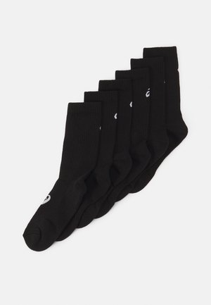 Black cotton socks. Ribbed texture, crew length, features white logo on the side. Set of six pairs displayed in a row.