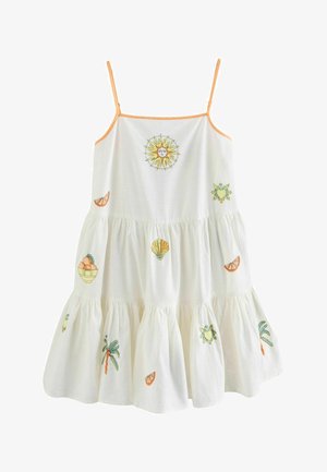 Fehér pamut ruha narancssárga pántokkal, hímzett nap, pálmafák, gyümölcsök és tengeri kagylók díszítésével. Többrétegű fodros szegélye fokozza a térfogatot.