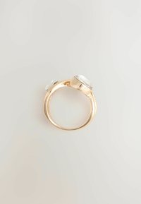 Guld ring med to klare, facetterede sten sat i rektangulære klør, glat ring med en poleret overflade og subtil teksturering omkring kanterne.