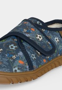 Chaussure en tissu bleue pour enfants avec motif ballon de football, texte « "Goal" », bride réglable en velcro et semelle en caoutchouc marron.