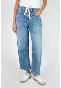 Jeans de mezclilla azul claro de pierna ancha con cintura ajustable, dos bolsillos frontales y un acabado ligeramente desgastado en las rodillas.