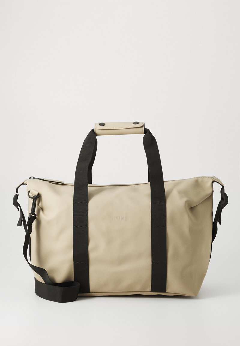 Beige waterproof duffel bag with black webbed straps, a detachable shoulder strap, and a snap-button handle. Features embossed logo.