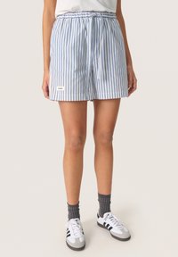 Shorts rayés bleu et blanc avec une ceinture élastique et un cordon de serrage, arborant un petit logo sur le côté. Tissu léger, coupe décontractée.