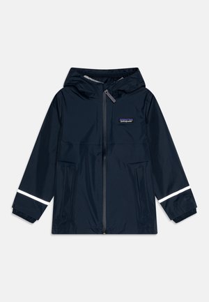 Giacca impermeabile blu navy con cappuccio, zip frontale, due tasche laterali e accenti riflettenti sulle maniche. Texture liscia.