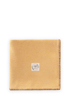 Žltý a biely tkaný textil so vzorom rybej kosti, hnedo prešitými okrajmi a stredovou nálepkou s nápisom "cigit BOHEME prémiová kvalita."