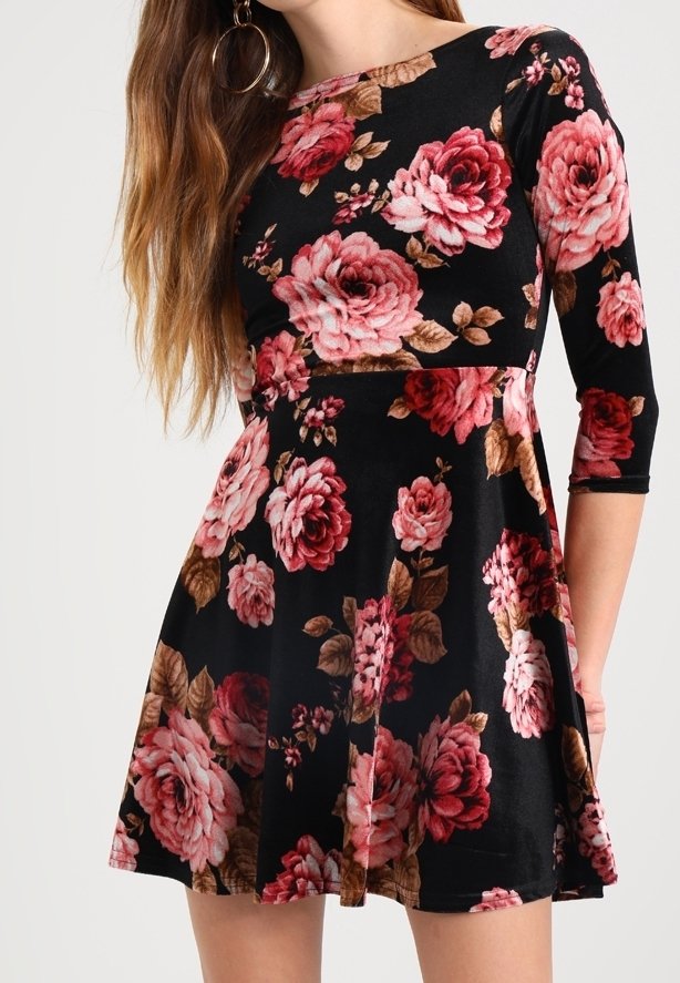 Robe noire à motifs floraux avec de grandes roses roses et des feuilles, à manches longues et jupe évasée. Fabriquée en tissu doux au toucher lisse.