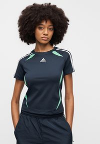 Námořnicky modré sportovní tričko se zelenými akcenty, krátkými rukávy a kulatým výstřihem. Na hrudi je logo Adidas a kontrastní pruhy na ramenou.