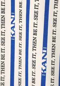 Texto negro repetido "ENTONCES SÍ. VÉALO." y texto azul "IKANI" sobre tela blanca con rayas verticales azules.