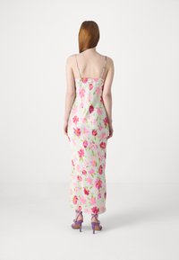 Μακρύ floral φόρεμα με λεπτές ρυθμιζόμενες τιράντες, με ανοιχτό πράσινο φόντο και σχέδια λουλουδιών σε ροζ, μωβ και κίτρινες αποχρώσεις.