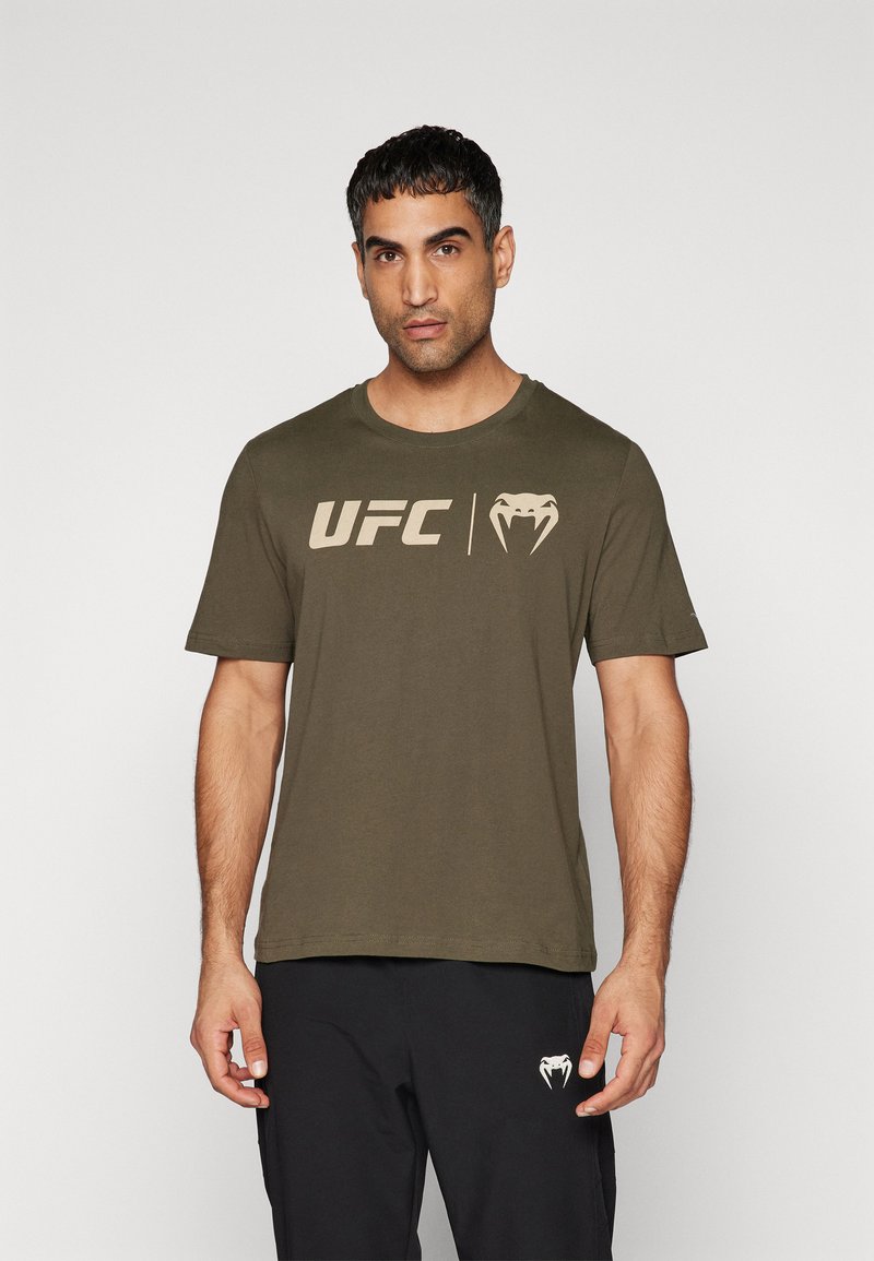 Oliven grøn bomulds T-shirt med rund hals, prydet med et stort beige UFC-logo og en slange grafik på forsiden. Korte ærmer, afslappet pasform.