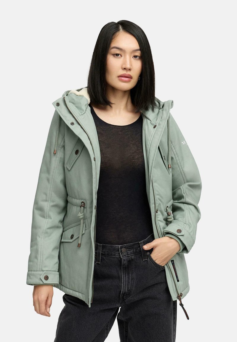 Light green, insulated parka with a hood, drawstring waist, and multiple pockets. Warm lining and zipper accents. Black top and dark pants.