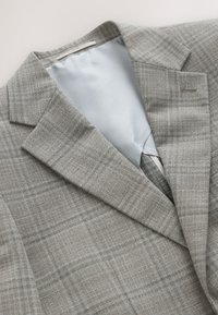 Blazer a quadri grigio con rever a intaglio, caratterizzato da una trama sottile e fodera azzurro chiaro. Include un bottone singolo e dettaglio con tasca.