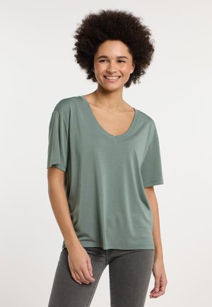 T-shirt vert à col en V avec des manches courtes, fabriqué en tissu doux. Coupe décontractée avec une texture lisse et sans motifs ni accessoires visibles.