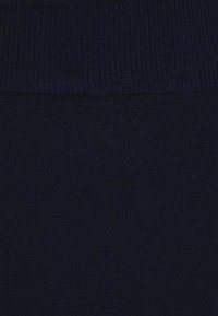 Dunkelblauer Pulloverstoff mit weicher Textur und einem gerippten Strickdesign am oberen Rand, das einen sanften Farbübergang erzeugt.