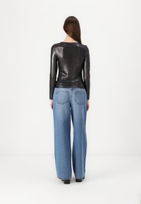 T-shirt preto de manga longa em ribana, combinado com jeans de denim azul claro, soltos, com bolsos traseiros e corte straight-leg.