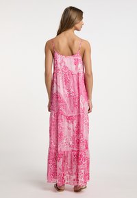 Rochie maxi fără măneci cu un model paisley și floral în nuanțe de roz, cu un design în straturi și țesătură ușoară și fluidă. Dispune de bretele subțiri.