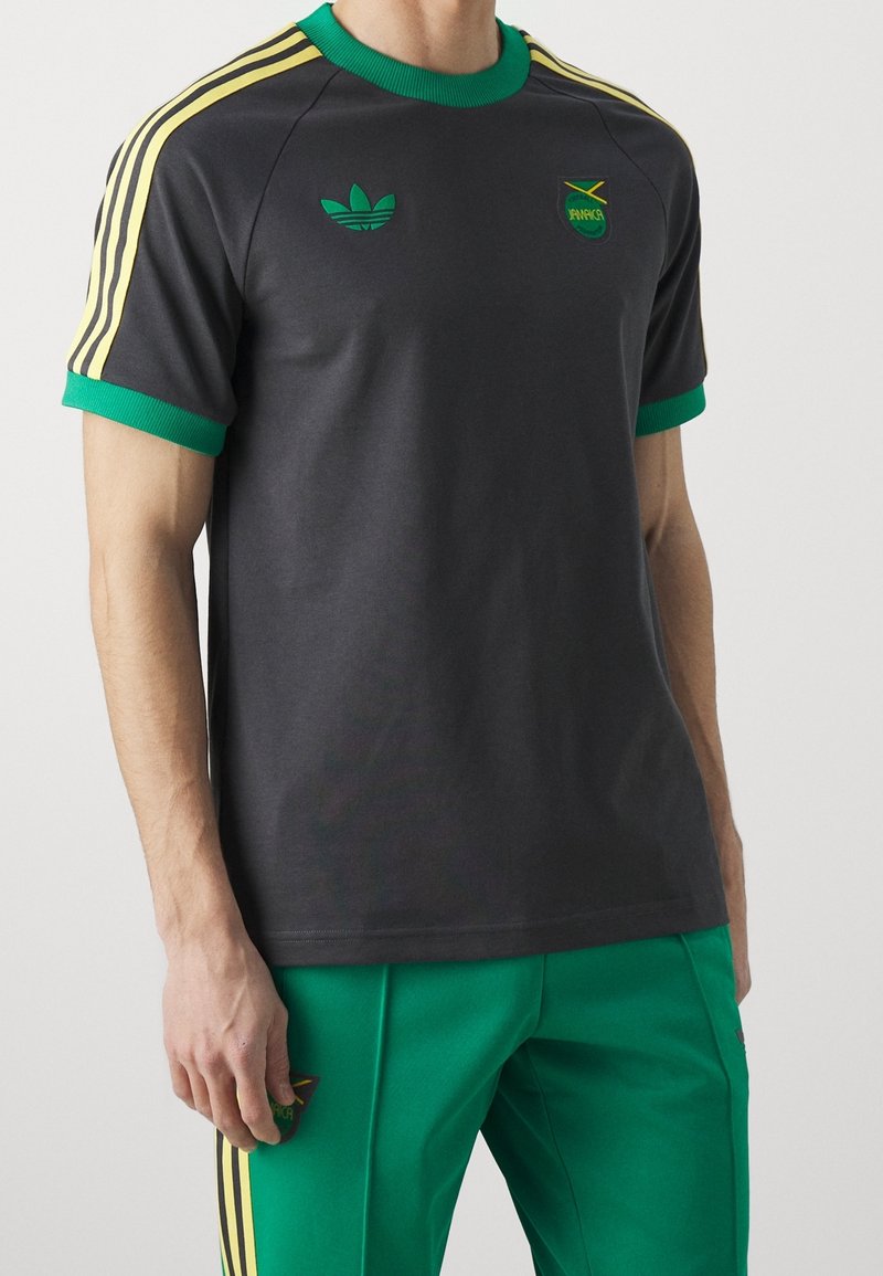 Grå bomullst-shirt med grön krage och ärmar, med gula Adidas-ränder och logotyper, designad för en figurnära passform.