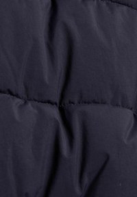 Mørk navy blå quilted stof med vandrette syninger og lette rynker og folder i materialet.