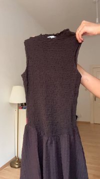 Sleeveless, dark brown dress with textured fabric, featuring a fitted top and a flared bottom. No prominent patterns, simple design.