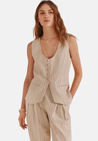 Beige gestreifter ärmelloser Weste mit tiefem V-Ausschnitt, fünfknöpfigem Verschluss und seitlichen Taschen. Der Stoff hat eine strukturierte Optik.