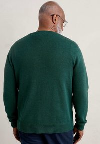 Pull en maille vert foncé, encolure ronde, poignets et ourlet côtelés, tissu texturé, manches longues, vu de dos.