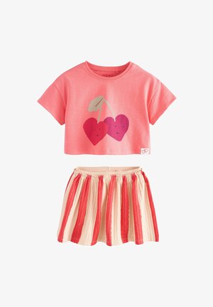 Rosa kortärmad t-shirt med en körsbärshjärt-grafik, ihop med en randig kjol i kräm, röd och korallfärger. Mjuk tyg, plisserad design.