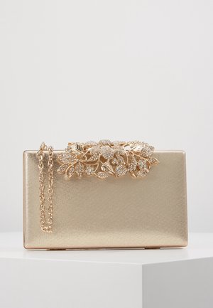Pochette rectangulaire dorée avec ornements floraux en cristal sur le dessus et une anse chaîne dorée assortie.