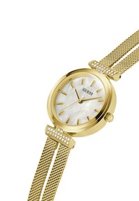 Montre en métal doré avec un boîtier rond, un cadran en nacre, des index en or et un bracelet en mesh avec des accents en cristal sur le fermoir.