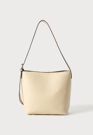 Beige Texturierte Schultertasche mit geschwungener Form, langem Träger und einem subtilen dunklen Rand entlang der Öffnung. Glatte Oberfläche mit minimaler Verzierungen.