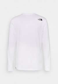 Långärmad vit t-shirt med rund halsringning och svart logotyp på övre ryggen. Tillverkad av mjukt bomullstyg.