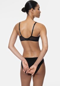 Conjunto de lencería negra que incluye un sujetador con espalda de malla y tirantes ajustables, acompañado de una braguita a juego. Textura suave, diseño minimalista.