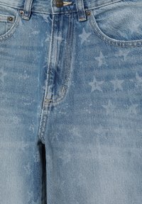 Jean en denim bleu clair avec des motifs d'étoiles délavées, des poches avant et une fermeture à bouton métallique à la taille.