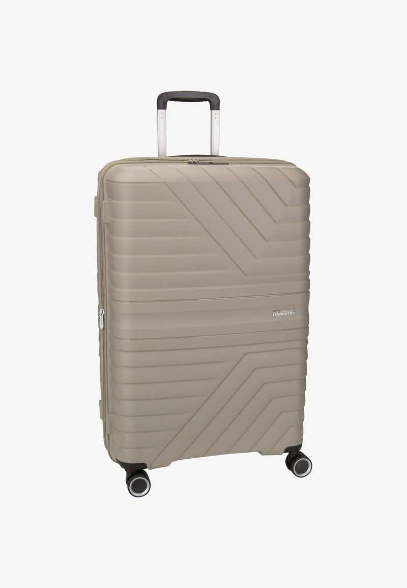 Valigia rigida beige con linee diagonali testurizzate, manico telescopico e quattro ruote girevoli per una facile mobilità.