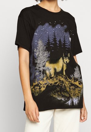 T-shirt en coton noir avec un motif de loup en jaune et bleu sur fond de forêt et ciel étoilé. Manches courtes, coupe décontractée.