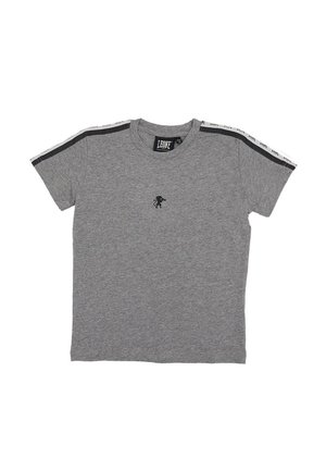 T-shirt gris à manches courtes, avec des bandes noires et blanches sur les épaules et un petit emblème noir représentant un lion sur la poitrine.