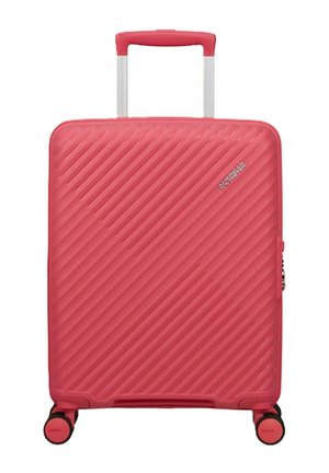 Valigia rigida rosa con scanalature diagonali, manico telescopico, quattro ruote girevoli e logo American Tourister sulla parte frontale.