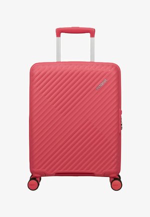 Valigia rigida rosa con scanalature diagonali, manico telescopico, quattro ruote girevoli e logo American Tourister sulla parte frontale.