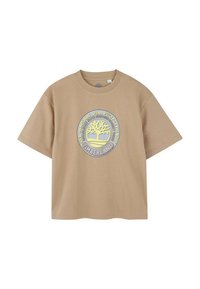 Lichtbruin T-shirt met korte mouwen, gemaakt van katoen. Bevat een cirkelvormig Timberland-logo met een boomontwerp in het midden en tekst eromheen.