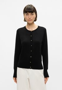 Cardigan nero con maniche lunghe, scollo rotondo e chiusura con bottoni. Presenta bordi a coste e bottoni in tono oro per un tocco di classe.