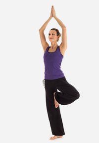 Purple athletic tank top paired with black loose-fitting yoga pants. The figure stands on one leg with hands raised above the head.