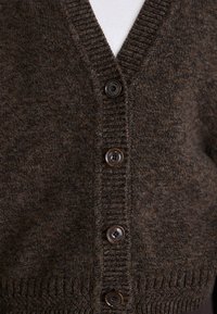 Bruine wollen cardigan met een V-hals, voorzien van vijf plastic knopen en ribbelafwerking langs de randen, met een gestructureerd breipatroon.